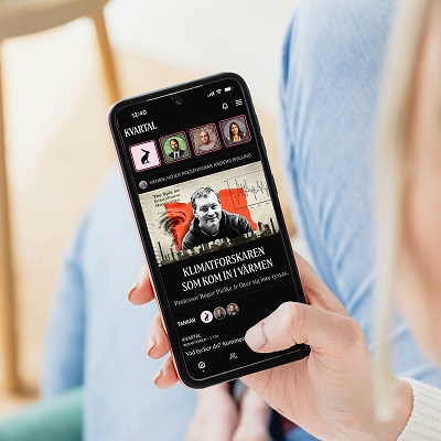 En person håller i en mobiltelefon där tidningen Kvartals app används.