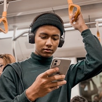 En person står på tunnelbanan och tittar i sin telefon.